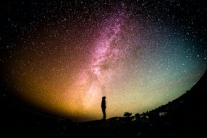 A person standing in front of a night sky looking at the stars