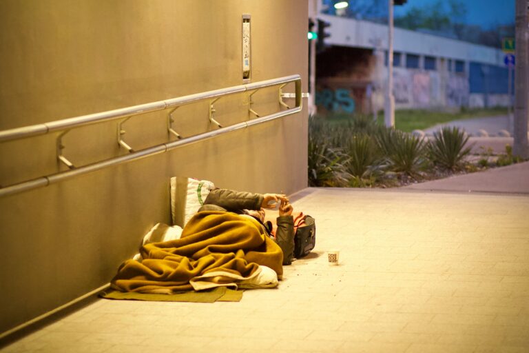 A homeless man lying down on the side of a pathway